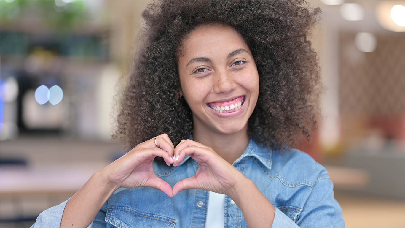 A woman makes a heart sign with her hands