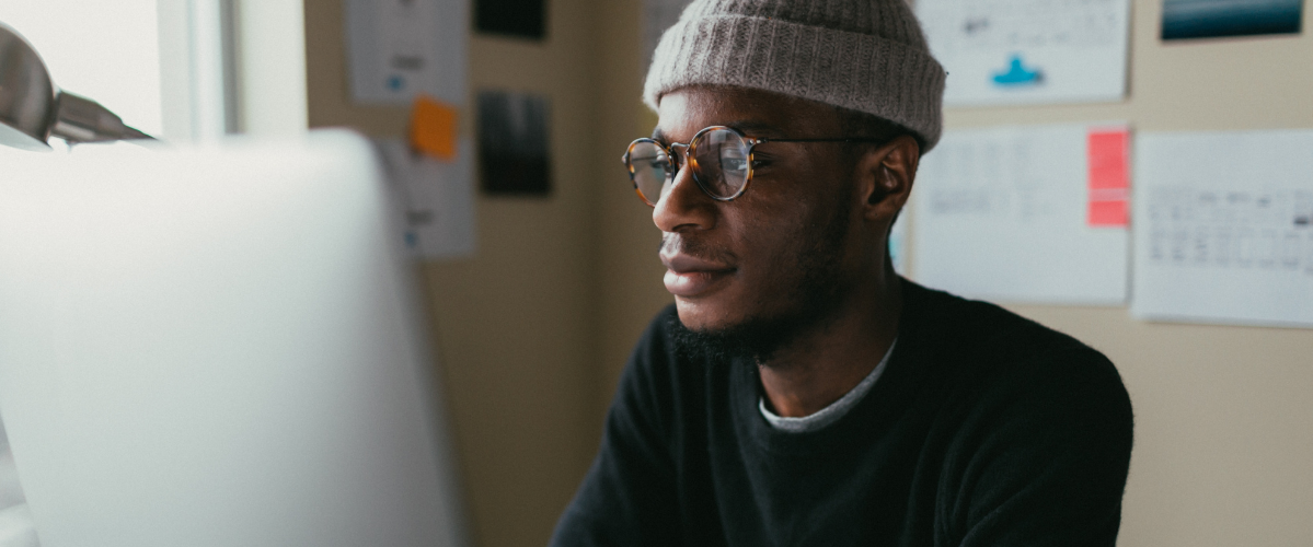A man wearing glasses reads something on a laptop