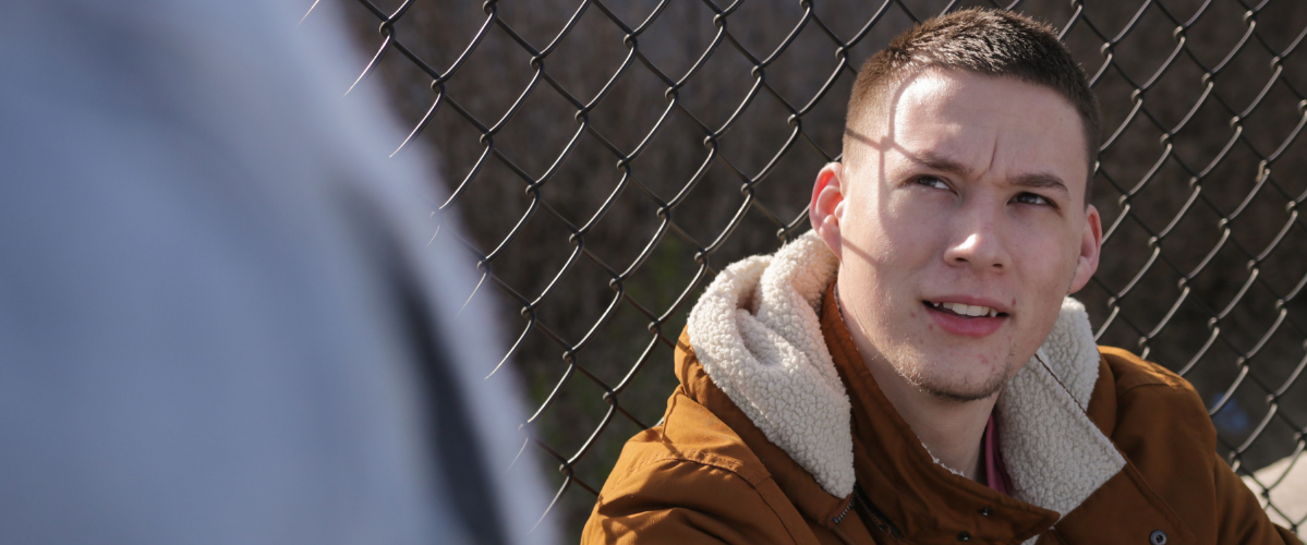 a person leans against a wire fence outside