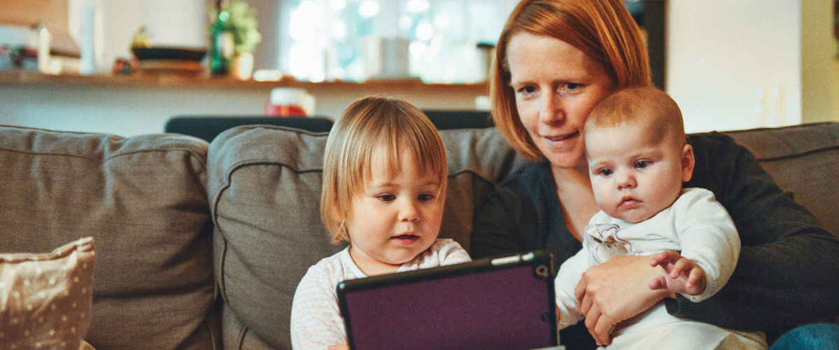 a mother with two children watch something on a tablet